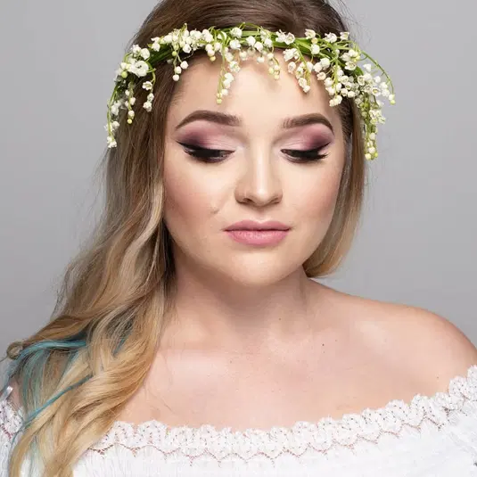  Kobieta z wiankiem z białych kwiatów na głowie, elegancki makijaż, długie blond włosy, romantyczny portret. 