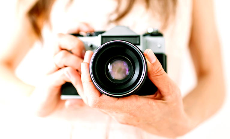  Osoba trzymająca lustrzankę analogową, zbliżenie na obiektyw aparatu fotograficznego, profesjonalna fotografia w stylu retro. 