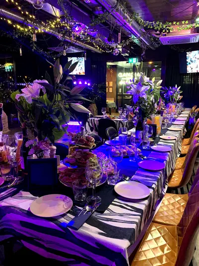  Luksusowo udekorowany stół bankietowy z eleganckim nakryciem, kwiatami i nastrojowym oświetleniem w nowoczesnej restauracji. 