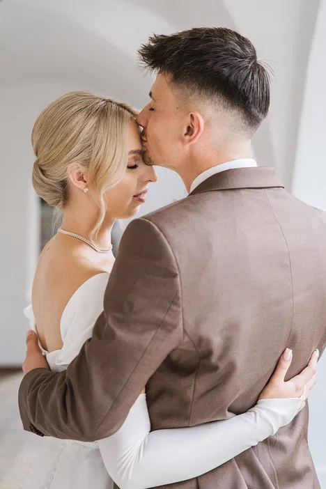 Panna młoda i pan młody przytulają się na eleganckim ślubie, zamknięte oczy, miłość, romantyczna atmosfera.