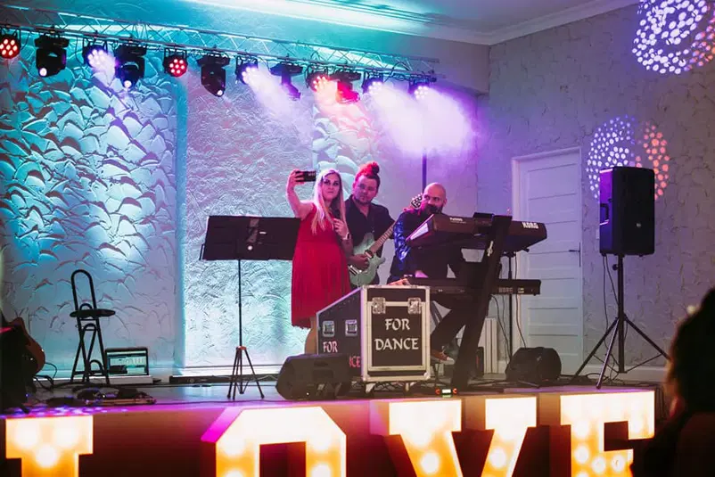  Grupa muzyczna występująca na scenie z neonowym napisem LOVE, zespół na koncercie w kolorowym oświetleniu. 