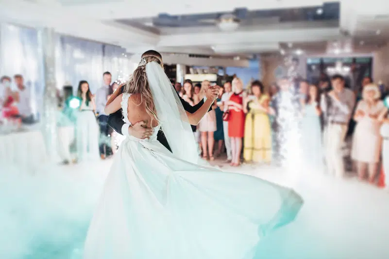  Pierwszy taniec pary młodej na weselu, romantyczny moment, goście w tle, wesele w eleganckiej sali, ślubna suknia z welonem. 