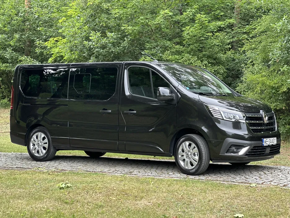 Czarny minivan na tle zielonego lasu, lato, nowoczesny design, parkowanie na trawie.