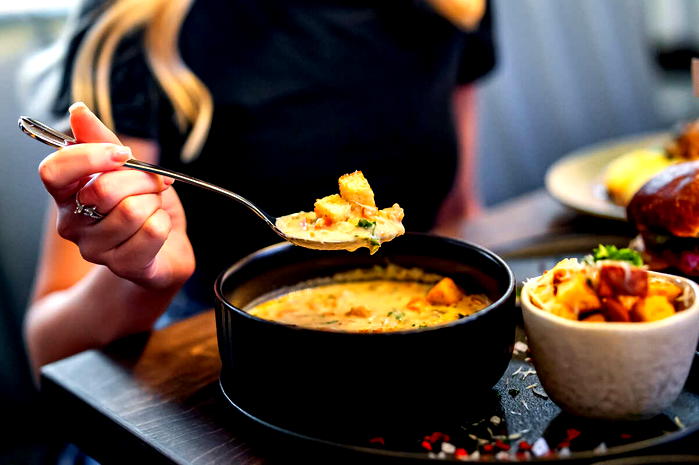  Osoba jedząca kremową zupę z grzankami w eleganckiej restauracji. 