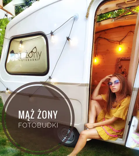  Mobilna fotobudka Mąż Żony, przyczepa z oświetleniem dekoracyjnym, wnętrze z drewnianymi elementami, kobieta w żółtej sukience na progu przyczepy. 