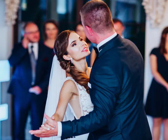  Pierwszy taniec młodej pary na weselu, panna młoda w białej sukni ślubnej z welonem, pan młody w eleganckim garniturze, romantyczna atmosfera. 