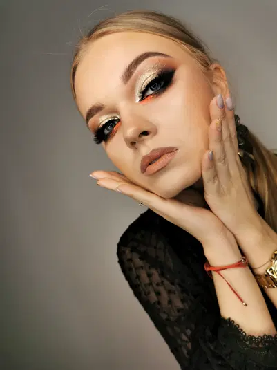  Portret kobiety z efektownym makijażem oczu w stylu glamour, złote cienie, eyeliner i długie rzęsy. Elegancka stylizacja na wieczór. 
