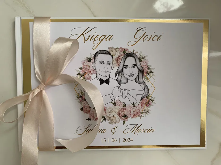 Księga gości weselnych z ilustracją pary młodej, zawiązana jasną wstążką, otoczona kwiatowym motywem oraz datą ceremonii, elegancki design.