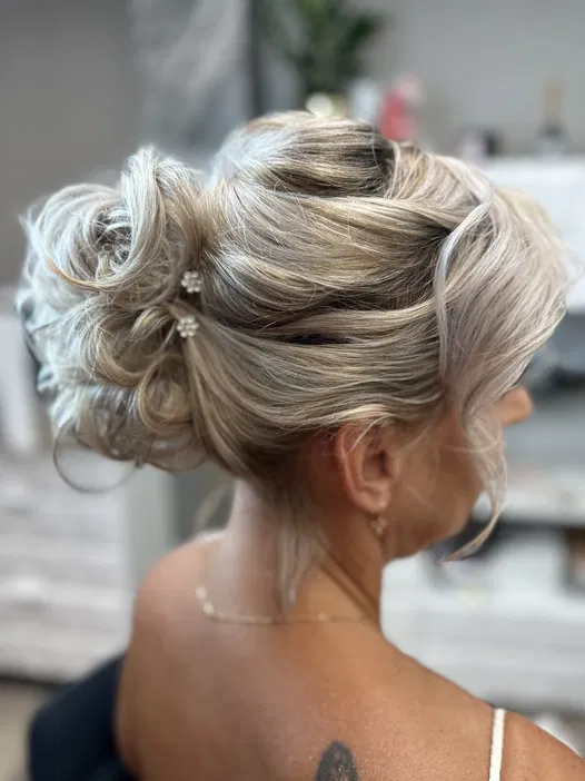 Blond włosy upięte w elegancki kok z ozdobnymi wsuwkami, widok z boku.