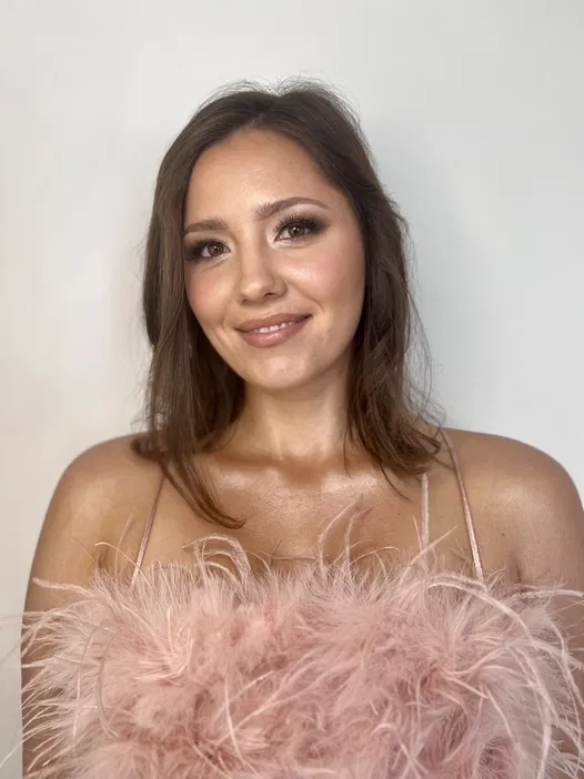 Nieznana kobieta w eleganckiej sukience z piórami, portret na jasnym tle.