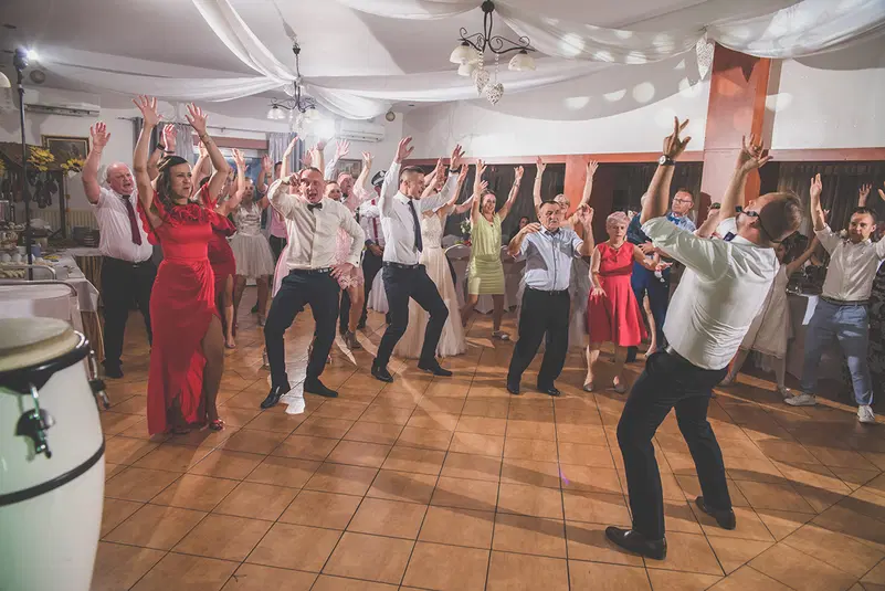  Grupa ludzi tańcząca podczas wesela w eleganckiej sali bankietowej. 