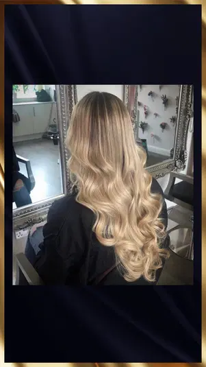  Długie blond włosy z luźnymi falami odbijające się w lustrze w salonie fryzjerskim. 