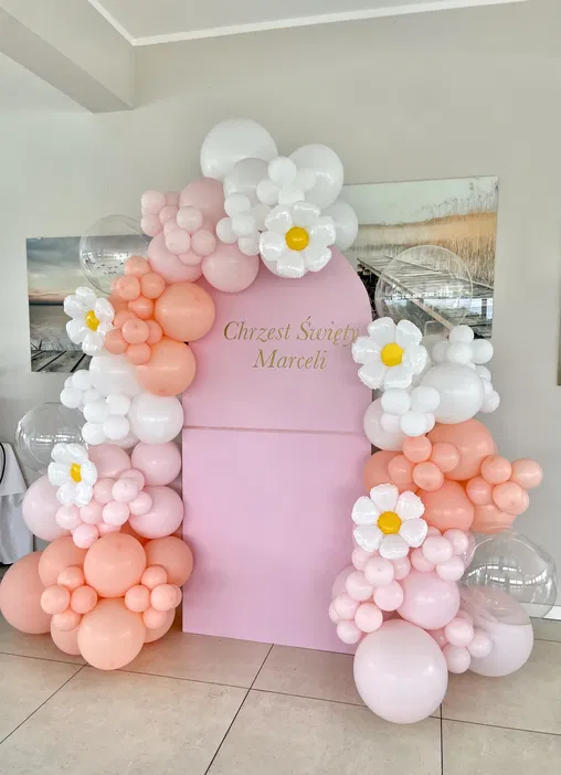 Dekoracja na chrzest święty z balonów w pastelowych kolorach z kwiatami na różowym tle.