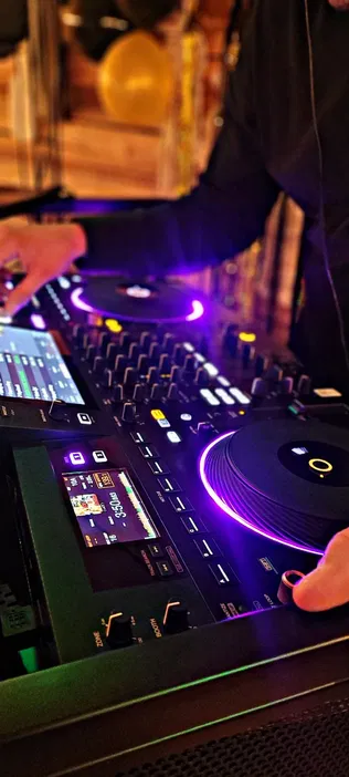 DJ grający na konsolecie z oświetleniem LED na imprezie muzycznej.