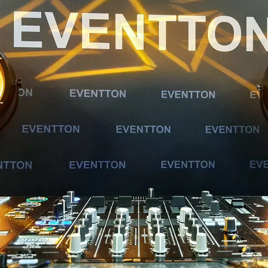  Mikser DJ na tle brandingowym Eventton z oświetleniem scenicznym. 