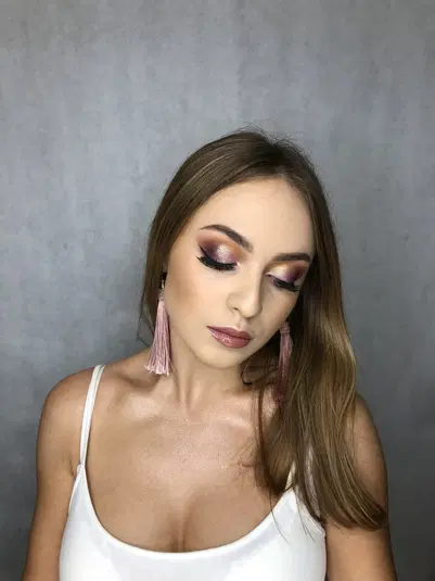  Woman with pink tassel earrings and flawless makeup on a gray background. 