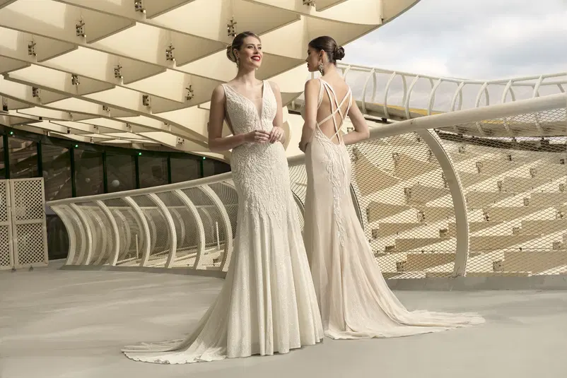  Dwie kobiety w eleganckich sukniach ślubnych na nowoczesnym tle architektonicznym. 