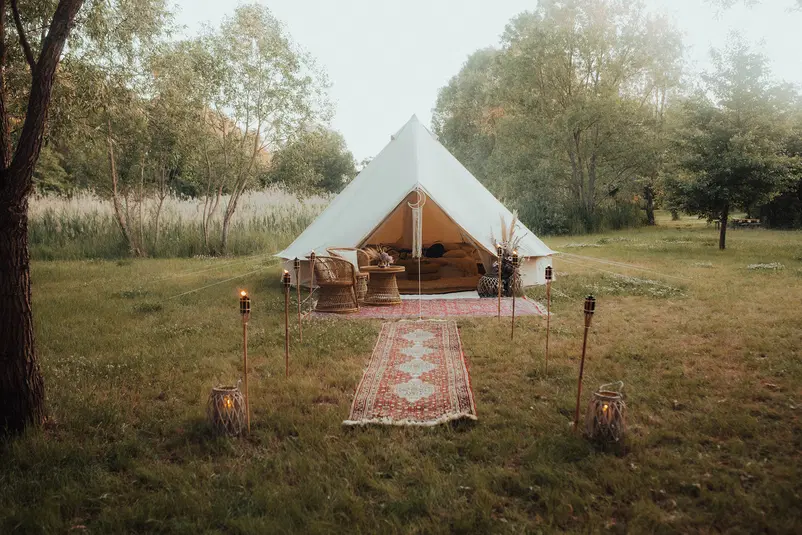  Namiot glampingowy w lesie, wyposażony w wygodne meble i dekoracje, otoczony przyrodą i zielenią, tworzy romantyczną atmosferę na kempingu. 