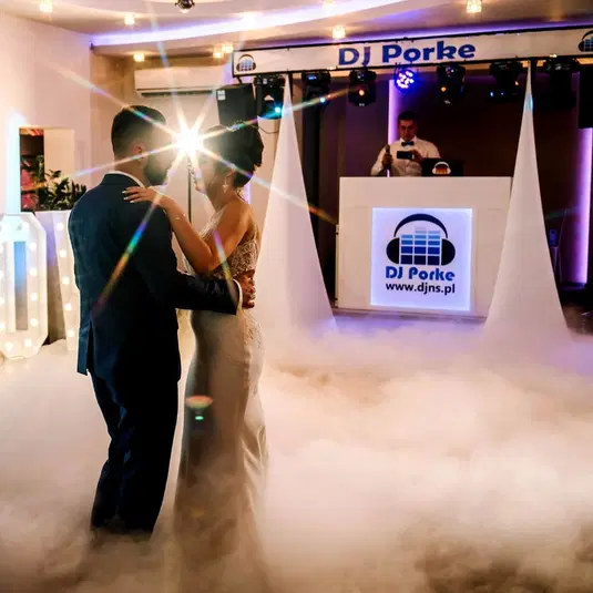  Pierwszy taniec pary młodej na weselu z DJ-em, światła i dym tworzące romantyczną atmosferę. 