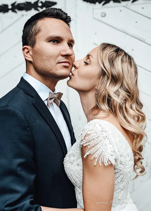 Para młoda, romantyczny pocałunek, eleganckie stroje ślubne, mężczyzna w garniturze, kobieta w koronkowej sukni, białe tło.