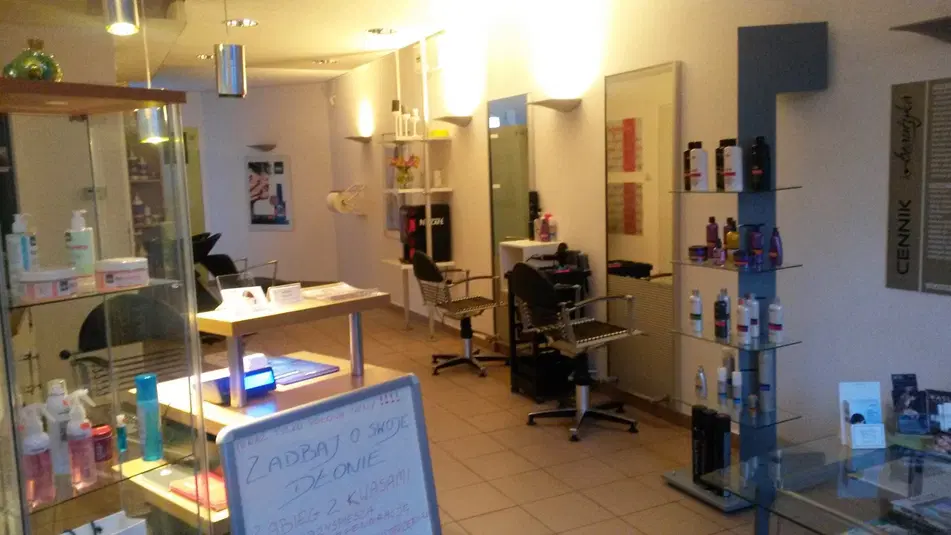  Wnętrze salonu fryzjerskiego z fotelami i półkami pełnymi produktów do pielęgnacji włosów. 