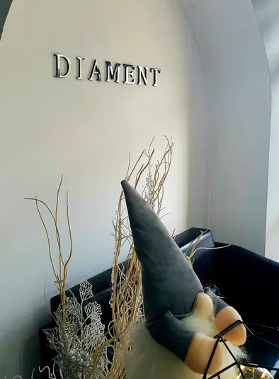  Wnętrze z napisem DIAMENT na ścianie, dekoracje z gałązkami i pluszowym krasnalem, świąteczny wystrój. 