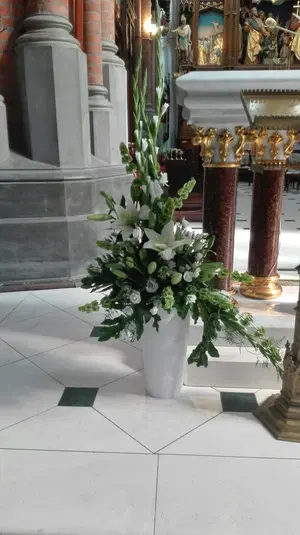  Kwiaty w białym wazonie w kościele, dekoracja floralna na tle kolumn i rzeźb, eleganckie kompozycje ślubne. 