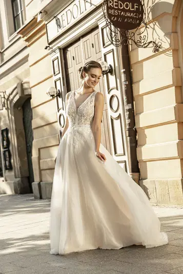  Kobieta w eleganckiej, koronkowej sukni ślubnej na tle zabytkowej architektury miejskiej. 