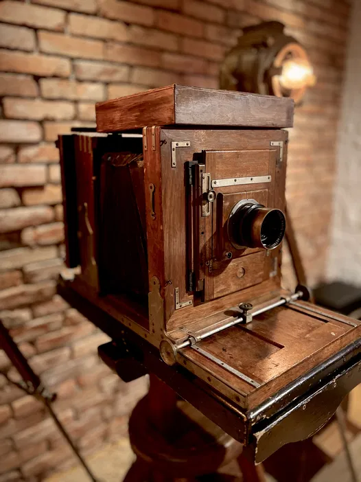Zabytkowy aparat fotograficzny na tle ceglanej ściany, retro sprzęt fotograficzny, vintage fotografia studyjna.