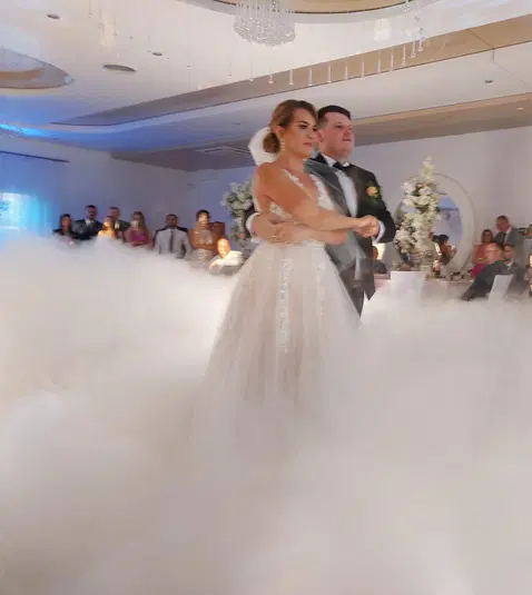  Para młoda tańcząca pierwszy taniec na weselu w otoczeniu niskiego dymu, elegancka sala bankietowa, romantyczna atmosfera. 