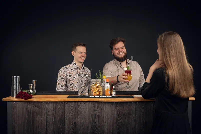  Barista podaje koktajl klientce przy barze, cieszący się towarzystwem w eleganckiej atmosferze. 
