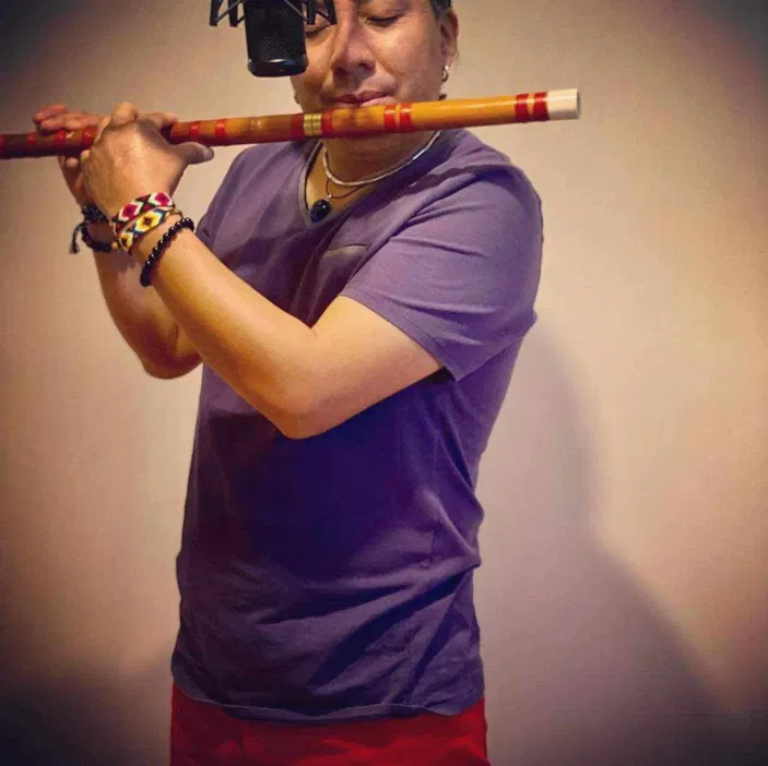 Muzyk grający na flecie, ubrany w fioletową koszulkę, studio nagrań, instrumenty dęte, sztuka muzyczna, występ solowy.
