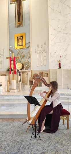  Harfistka grająca na harfie w kościele, sztuka i religia, wnętrze kościoła, muzyka sakralna, koncert harfowy w świątyni. 