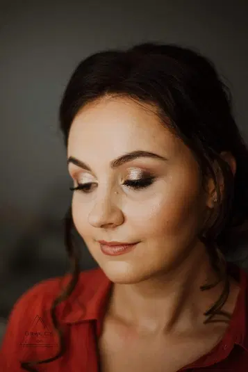  Nieznana kobieta w eleganckim makijażu, patrząca w dół, ciemne włosy, czerwony strój. 