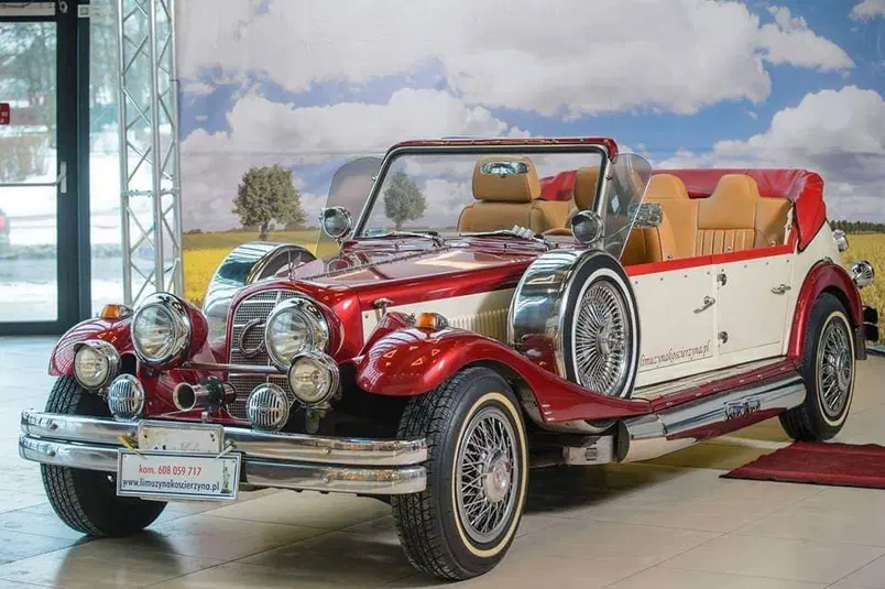  Kabriolet retro w eleganckiej czerwono-białej kolorystyce, klasyczne linie i luksusowe wykończenie, stojący w salonie samochodowym na tle malowniczego pejzażu. 