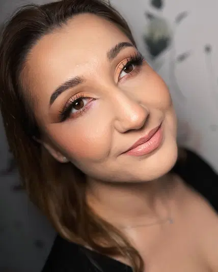 <!- Portret młodej kobiety z makijażem, patrzącej w górę, na neutralnym tle - inspiracje beauty, makijaż oczu, naturalny wygląd, uśmiech -> 