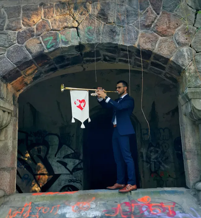 Mężczyzna w garniturze grający na trąbce w starym kamiennym łuku z graffiti, sztuka uliczna, muzyka na świeżym powietrzu.