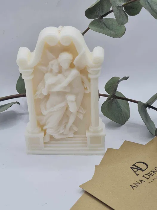 Elegancka świeca dekoracyjna w kształcie rzeźby, przedstawiająca parę w miłosnym uścisku, otoczoną przez delikatne liście, na tle minimalistycznych kart wizytowych.