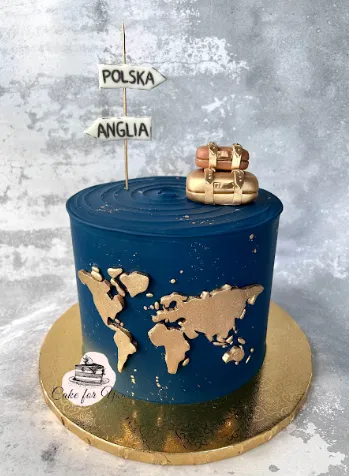 Tort z mapą świata, niebieskim tłem i złotymi akcentami, ozdobiony walizkami oraz tabliczkami z napisem Polska i Anglia na szczycie, na złotej podstawce, dekoracyjny tort podróżniczy.