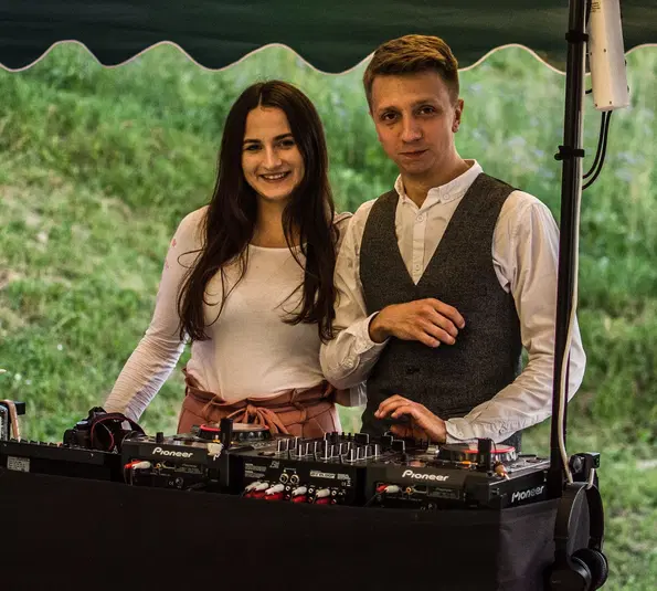 Para młodych DJ-ów przy konsolecie muzycznej na plenerowej imprezie. 