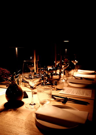  Elegancko nakryty stół w restauracji z kieliszkami do wina, świecami i stylową dekoracją, romantyczna atmosfera przy blasku świec. 