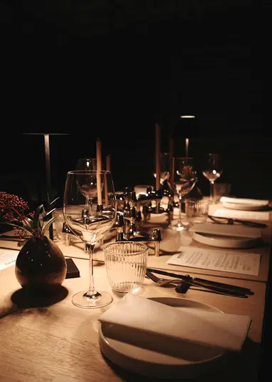  Elegancko nakryty stół w restauracji z kieliszkami do wina, świecami i stylową dekoracją, romantyczna atmosfera przy blasku świec. 