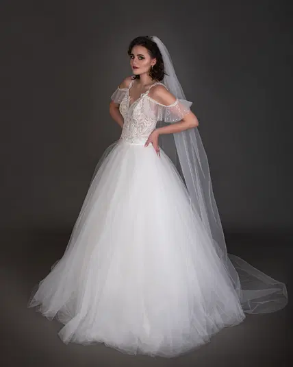  Elegancka panna młoda w koronkowej sukni ślubnej z trenem i welonem na ciemnym tle 