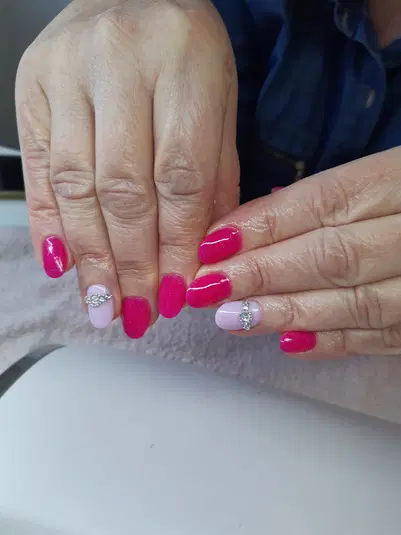  Stylowy manicure hybrydowy w odcieniach różu z ozdobnymi cyrkoniami na paznokciach. 