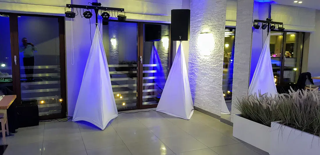  Nowoczesne wnętrze z oświetleniem scenicznym na imprezie, białe pokrowce na sprzęt audio, elegancki wystrój, atmosfera wieczorna. 