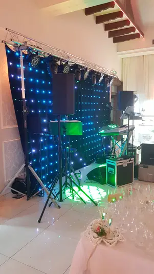 Scena muzyczna z kolorowymi światłami LED i sprzętem nagłaśniającym na imprezie weselnej. 