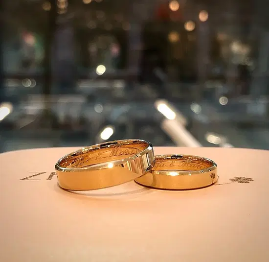 Złote obrączki ślubne z grawerem na eleganckiej powierzchni w tle. 