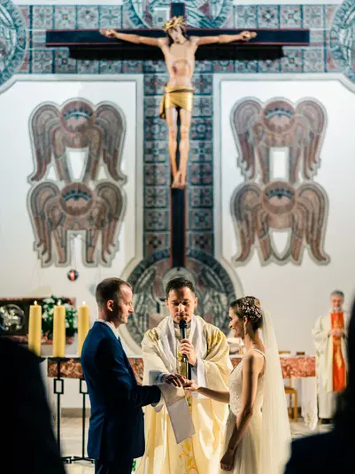  Ceremonia ślubna w kościele, młoda para podczas przysięgi małżeńskiej przed księdzem przy ołtarzu. 