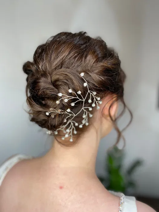 Romantyczna fryzura ślubna z ozdobną gałązką, włosy upięte w elegancki kok