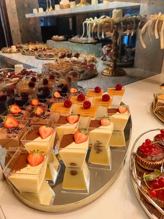 Desery w eleganckiej kawiarni z ciastkami czekoladowymi i owocowymi na złotej tacy.
